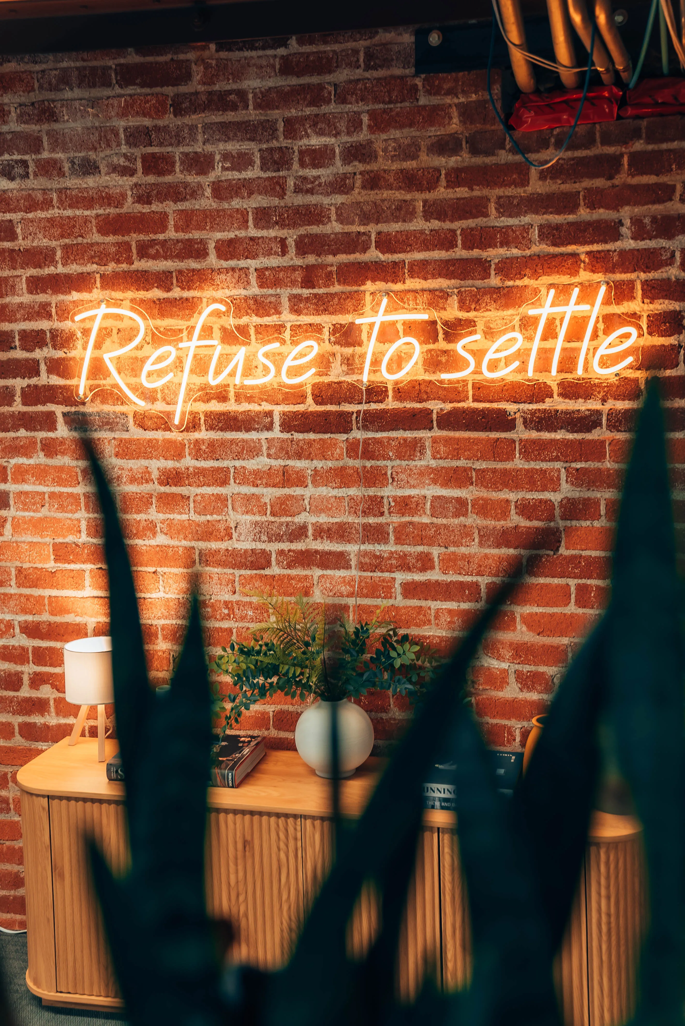 The Refuse to settle neon sign at the Outcast office